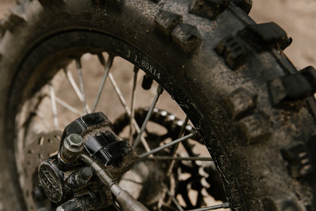 Detailed shot of a dirt bike's mud-streaked tire showcasing the treads and spokes.
