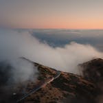 Stunning aerial view of clouds rolling over the Madeira mountains at sunrise, highlighting Curral Das Freiras.