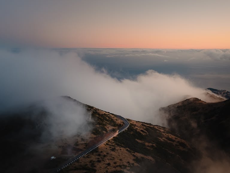 Stunning aerial view of clouds rolling over the Madeira mountains at sunrise, highlighting Curral Das Freiras.