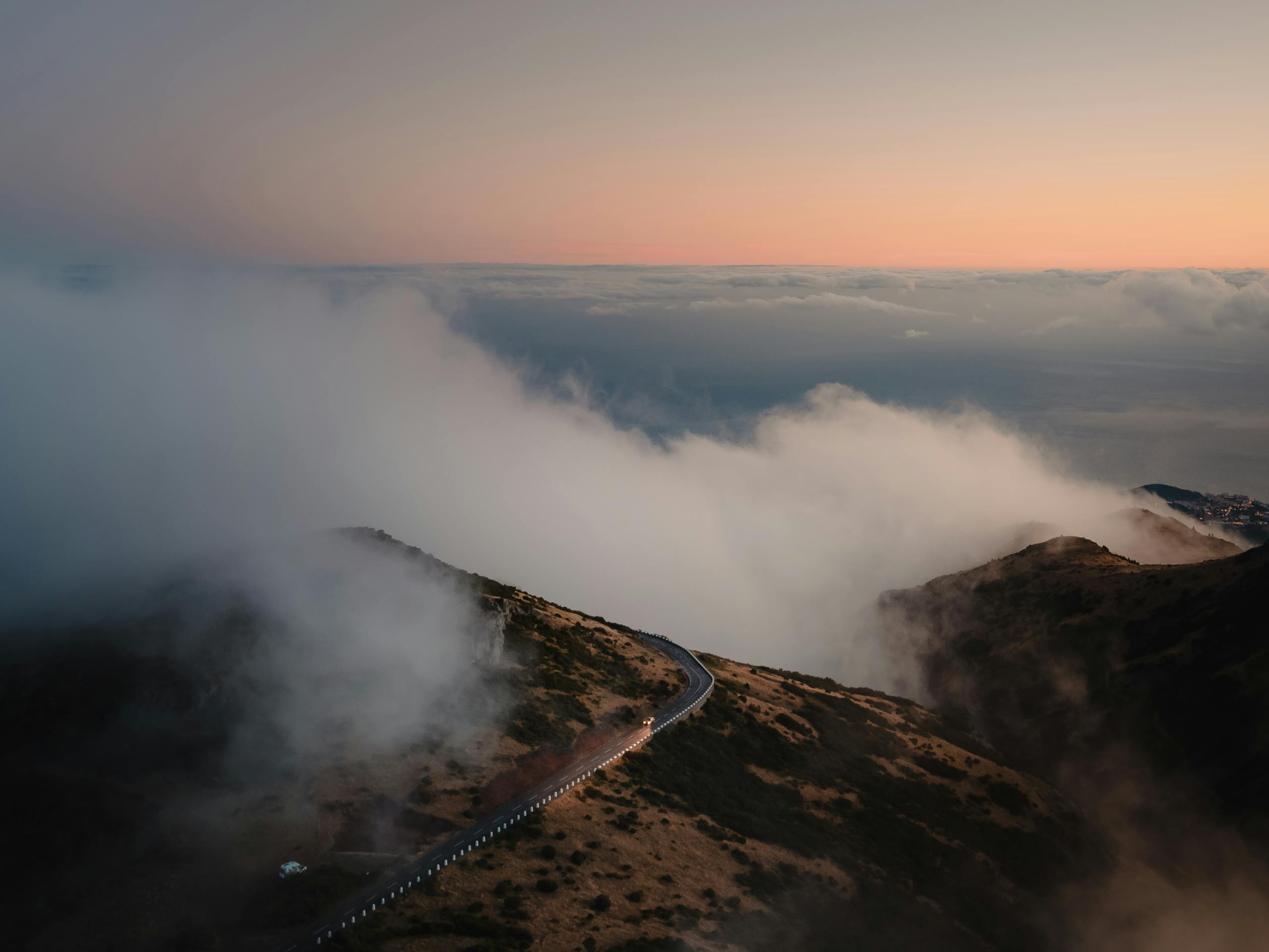 Stunning aerial view of clouds rolling over the Madeira mountains at sunrise, highlighting Curral Das Freiras.